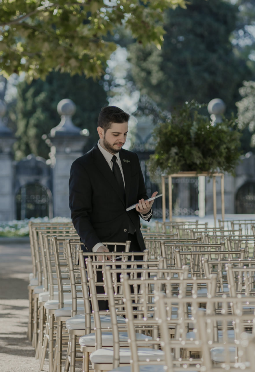 Nelson revisando las sillas doradas de una ceremonia al aire libre con el plan en la mano
