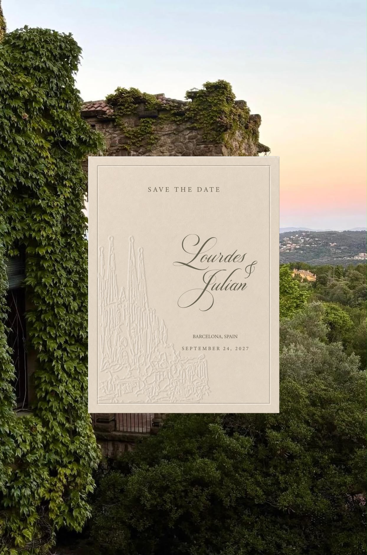 Tarjeta Save the Date de Lourdes y Julián con la Sagrada Família grabada, ante un muro de piedra cubierto de hiedra al atardecer