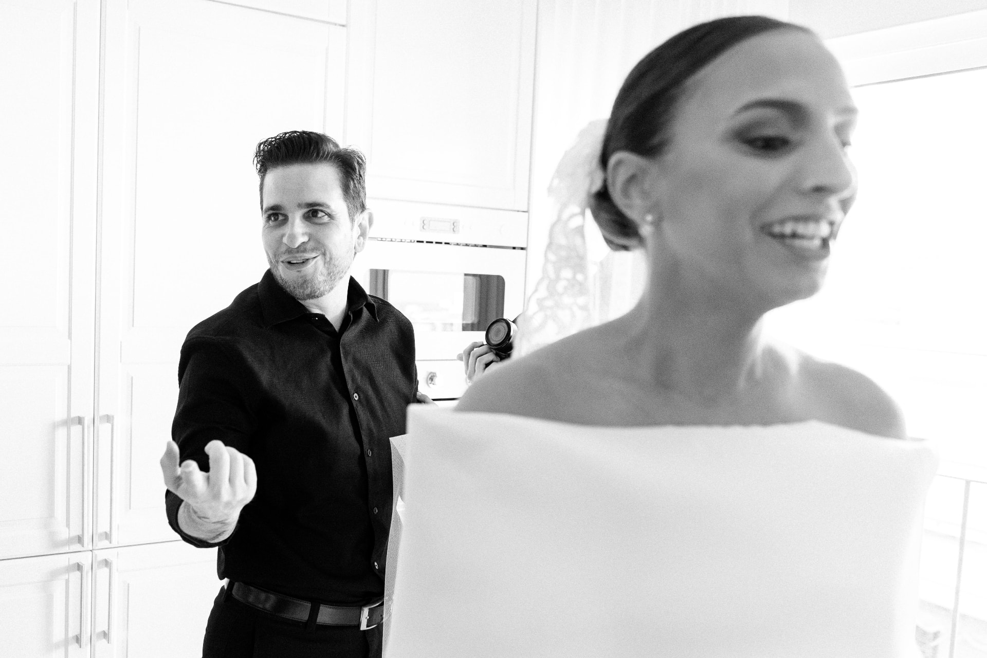 Nelson dirigiendo los preparativos de la novia en una habitación luminosa, en blanco y negro