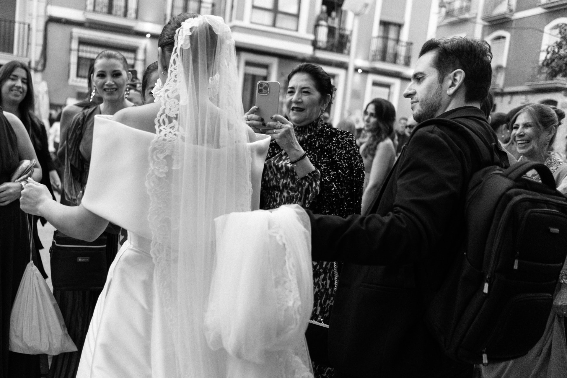 Equipo coordinando el paseo de la novia por una plaza histórica, en blanco y negro